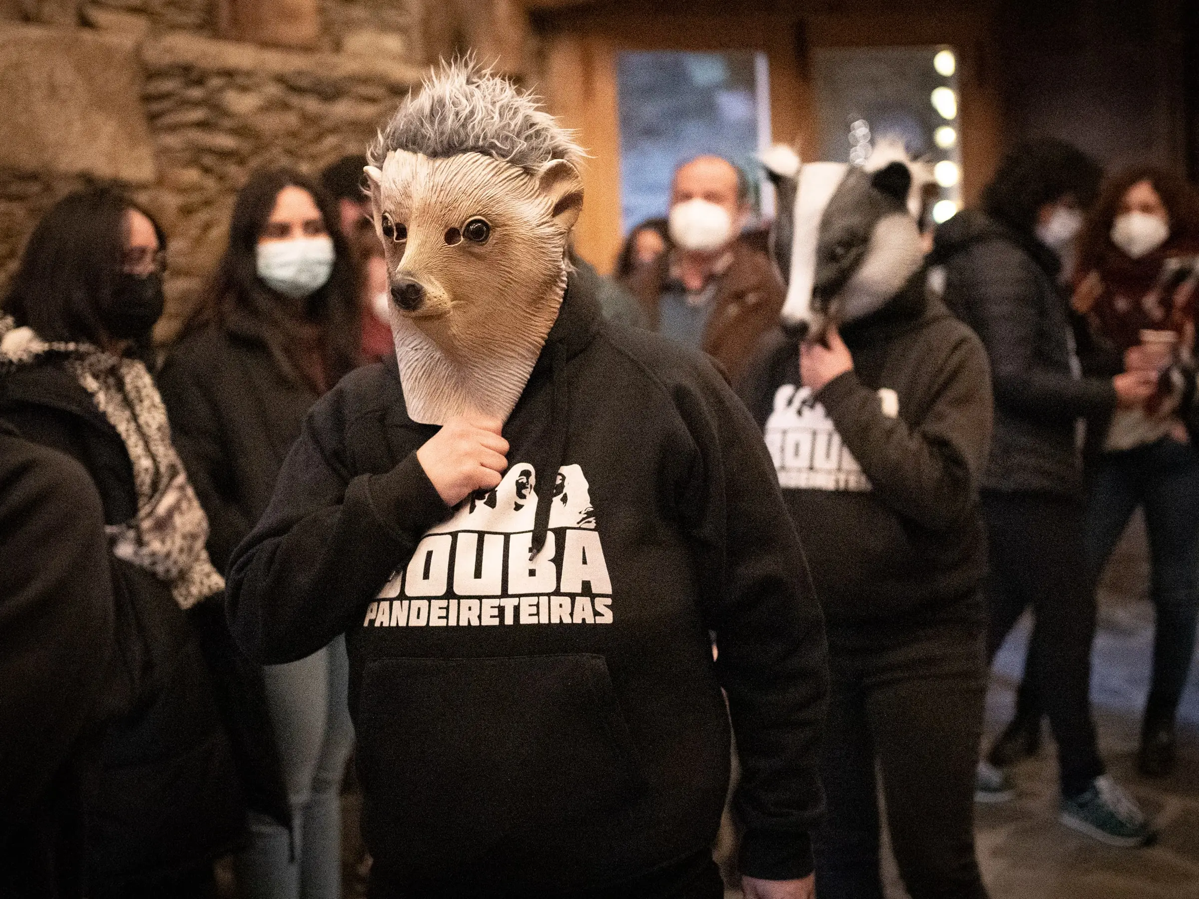 Dúas Bouba con máscaras de ourizo e teixugo entran entre a xente