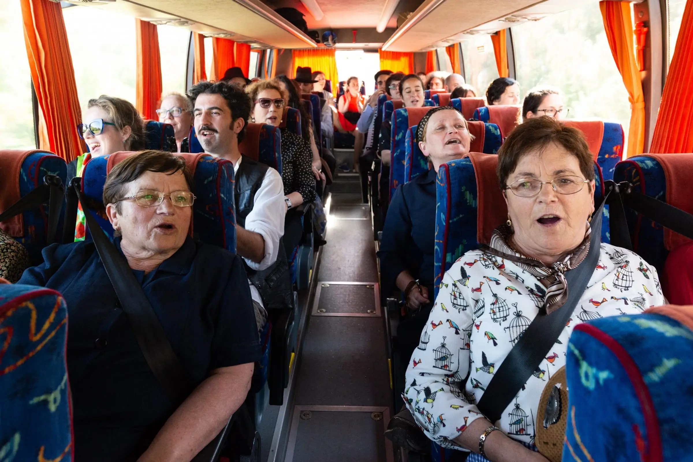 Mulleres maiores cantan sentadas nun autobús