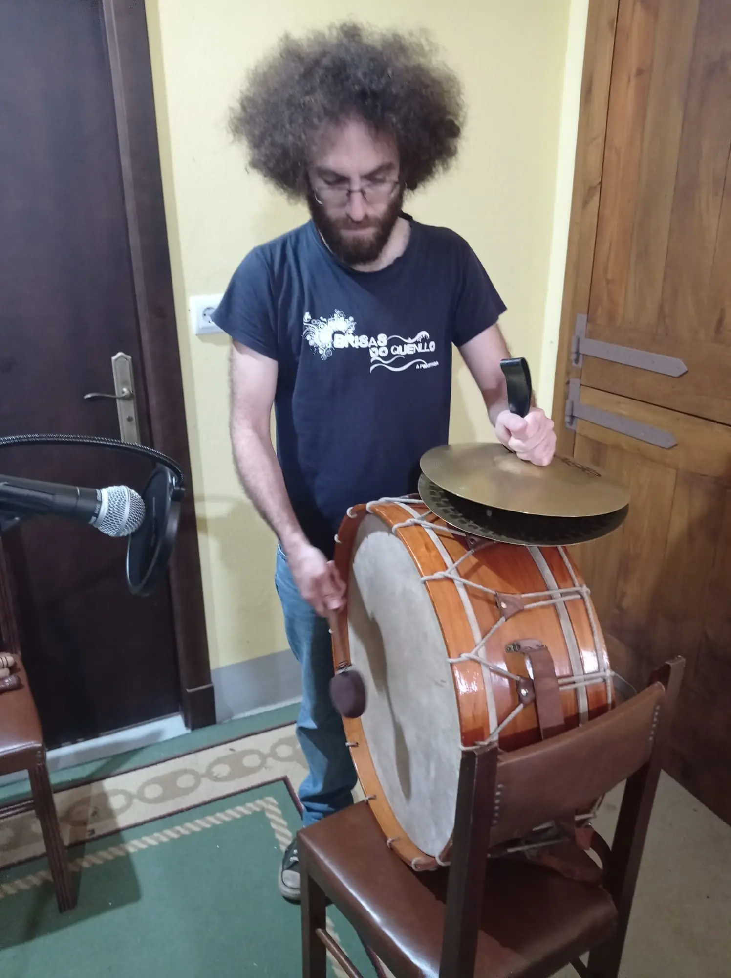Un músico de pelo rizo toca un bombo