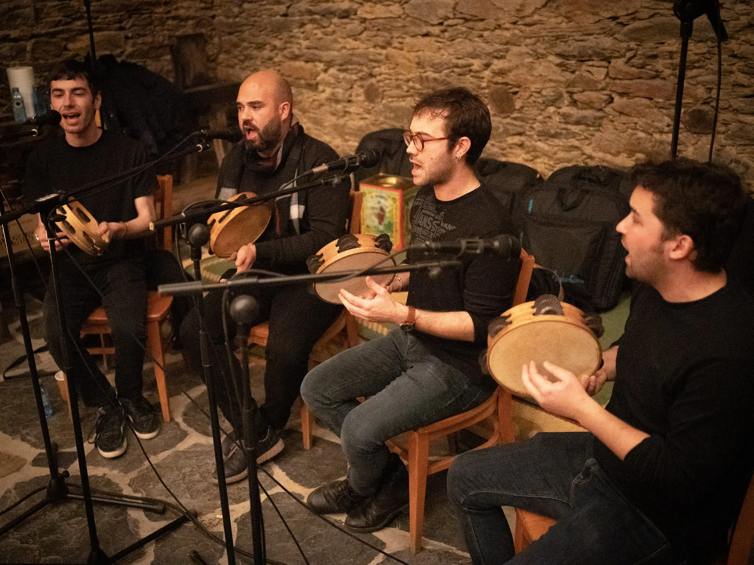 Catro pandeireteiros tocan sentados